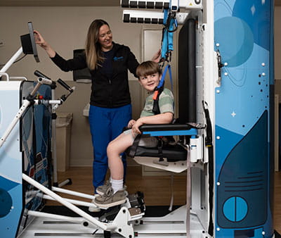 Nurse assisting happy boy in the Rise and Walk machine.