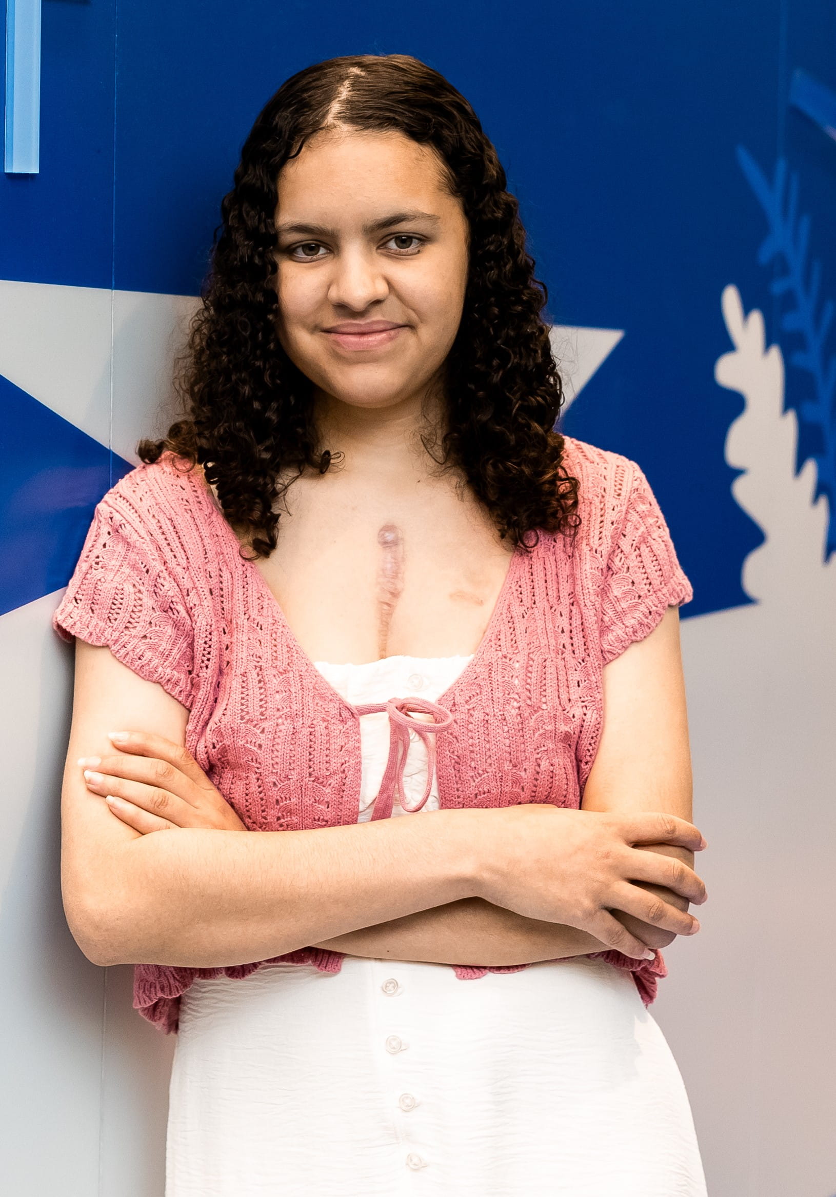 Dark-haired teen wearing white dress wtih pink knitted vest