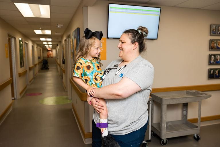 Smiling little girl being held by nurse.