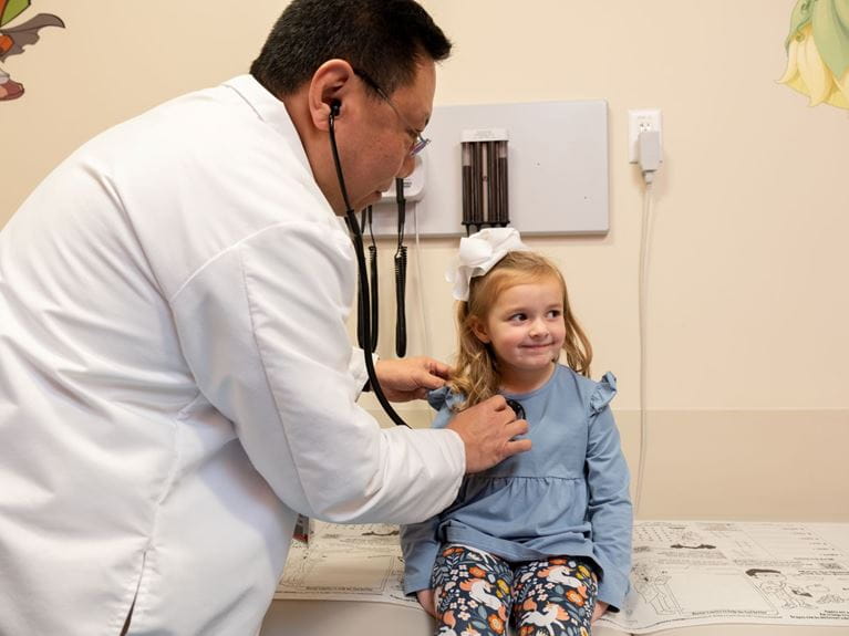 Doctor listening to little girl's heart beat. 